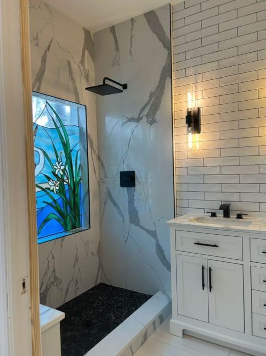 The same bathroom after: walk-in shower in large-format marble-look porcelain, matte black fixtures and a new vanity